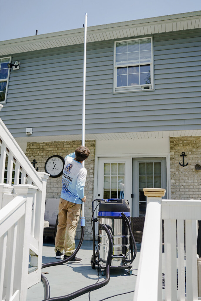 Pure Reflections technician performing professional gutter cleaning using a high-reach vacuum pole system at a home in Charleroi, PA.