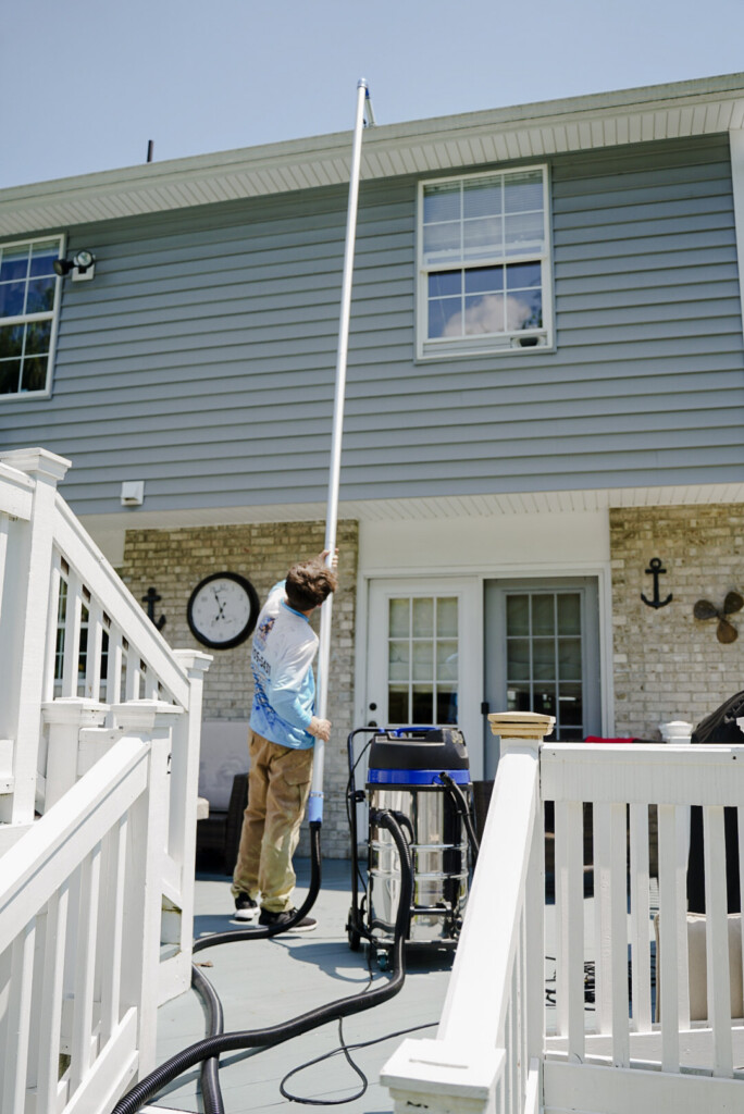 Pure Reflections technician performing professional gutter cleaning using a vacuum pole system at a home in Ginger Hill, PA.