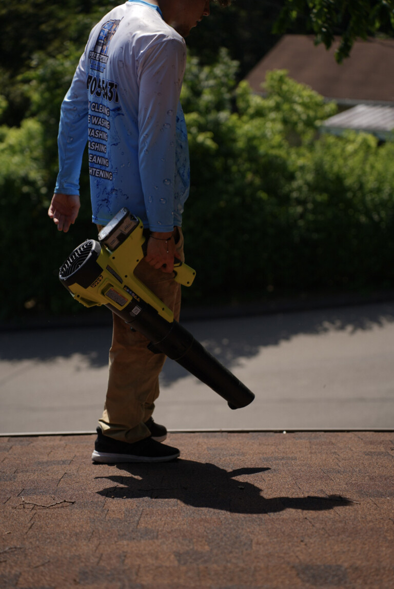 Gutter cleaning service in Oakdale, PA with technician walking roofline using a commercial leaf blower to remove debris from gutters.
