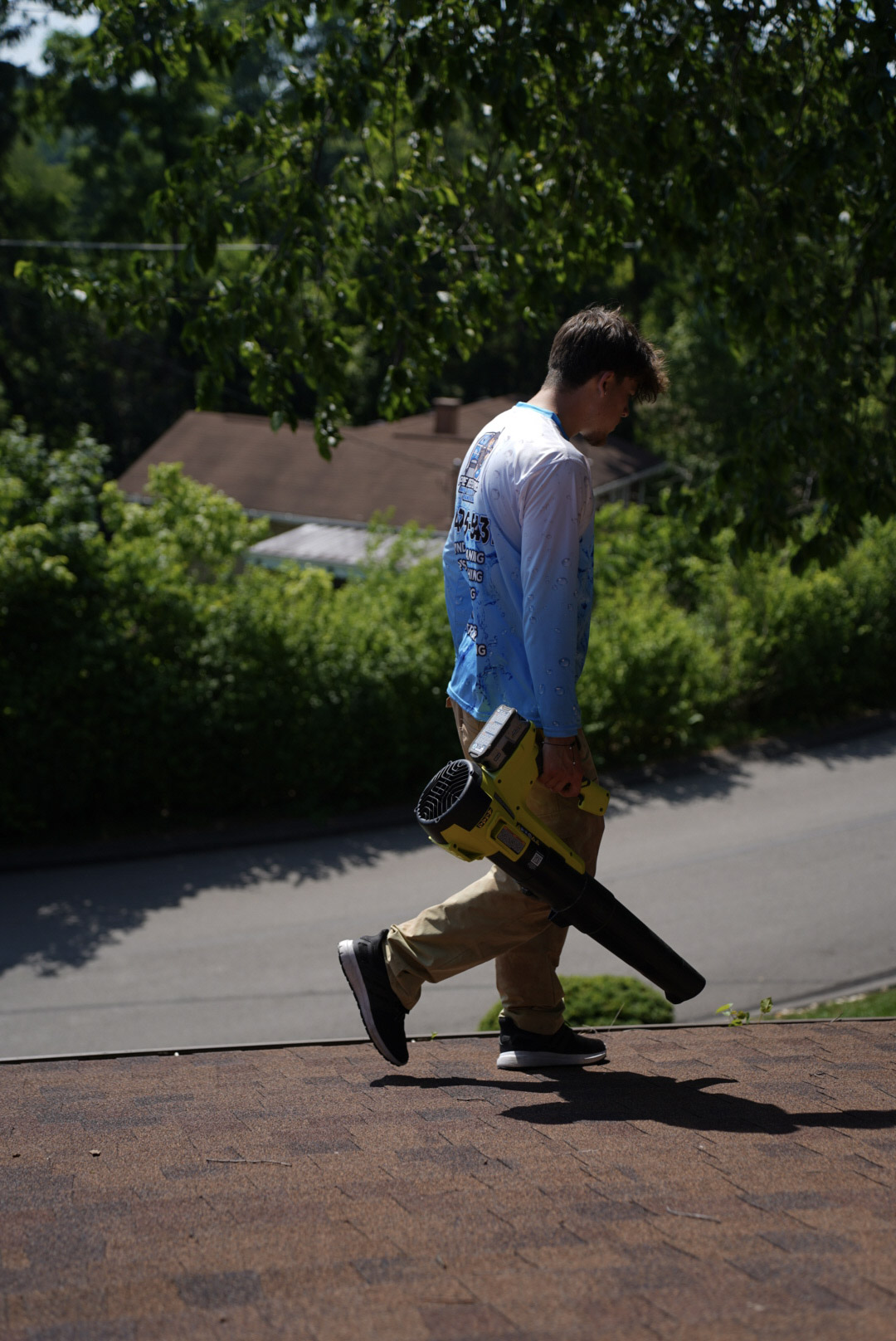 Gutter cleaning service in Presto, PA with technician walking roofline using a commercial blower to remove leaves and debris from gutters.