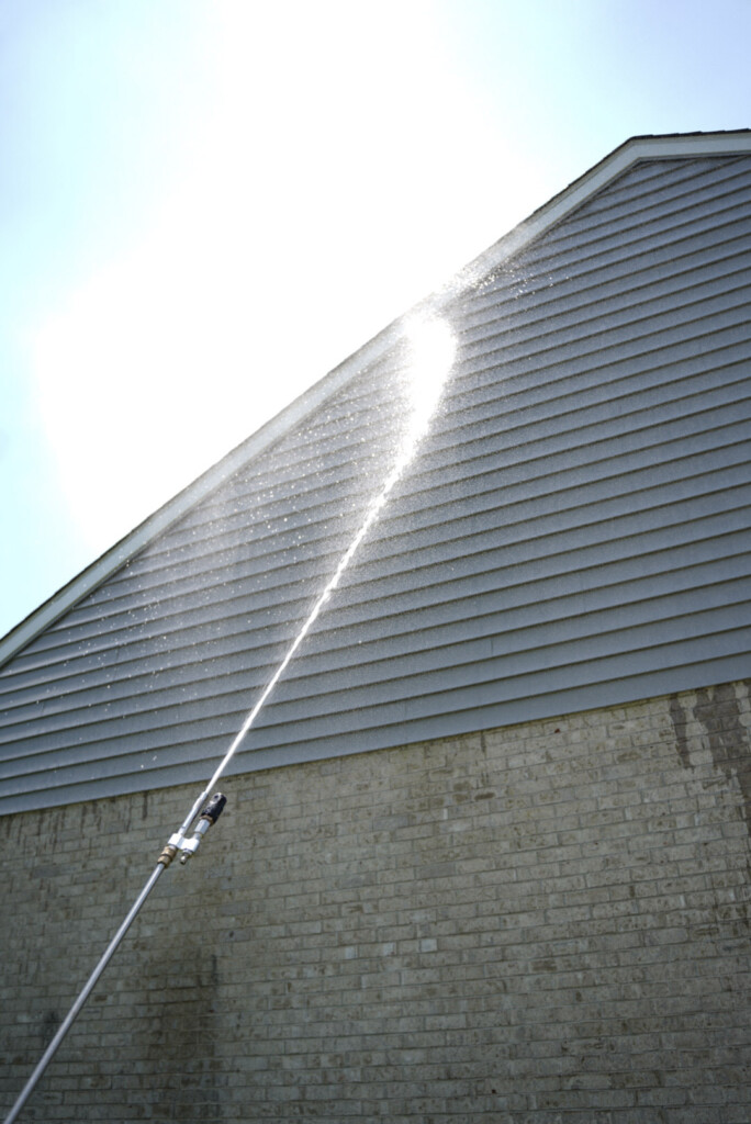 Soft washing upper vinyl siding on a residential home in McDonald, PA to remove algae and organic staining.