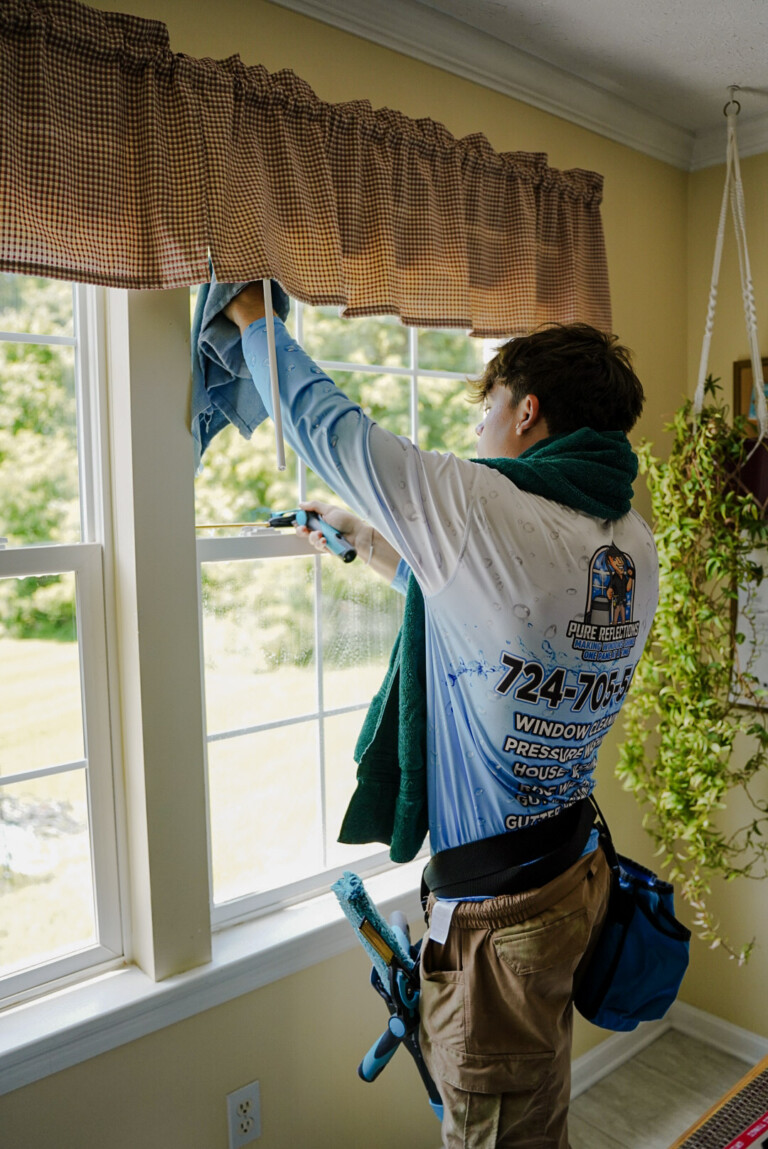 Pure Reflections technician cleaning interior windows in a home in Mars, PA.
