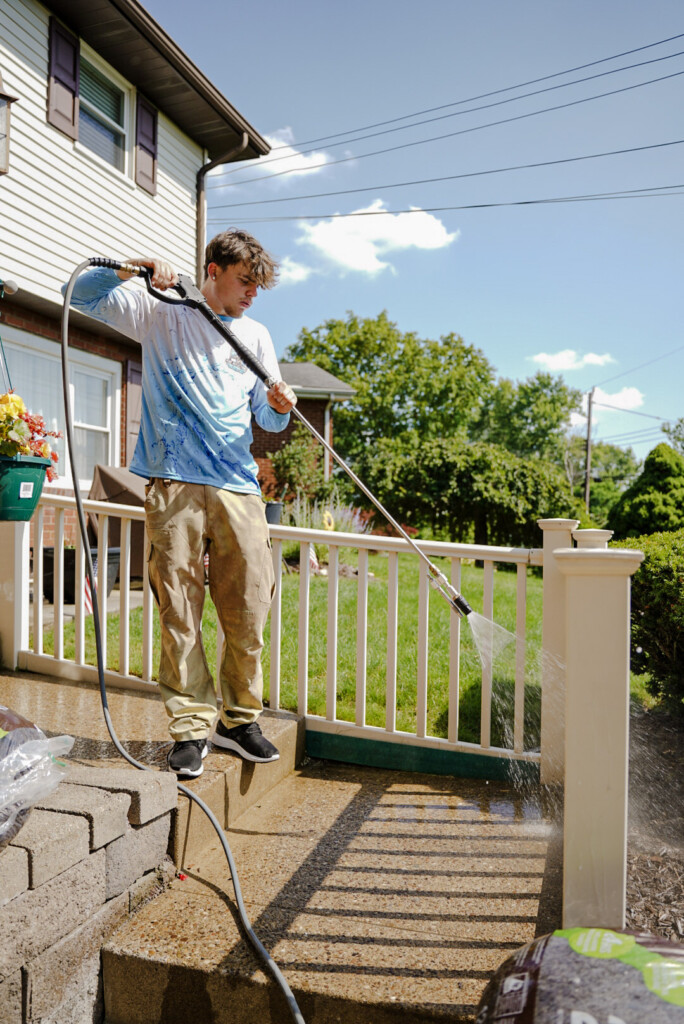 Pure Reflections technician pressure washing concrete steps and porch railing at a residential home in McMurray, PA.