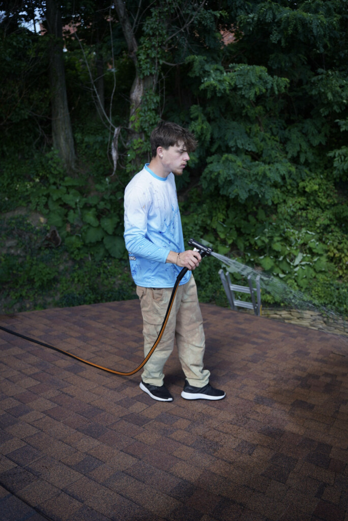 Roof cleaning service in Eighty Four, PA applying a soft wash solution to remove algae stains from asphalt shingles.