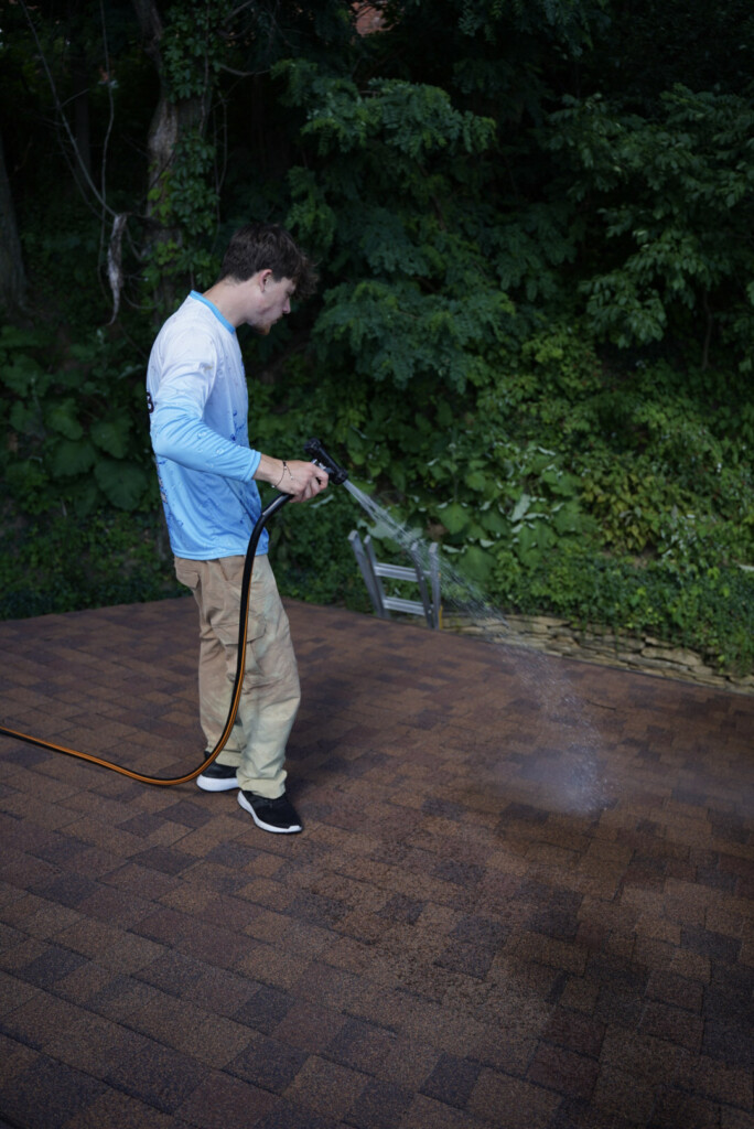 Roof cleaning service in South Point, PA applying a soft wash treatment to asphalt shingles to remove algae and dark staining.