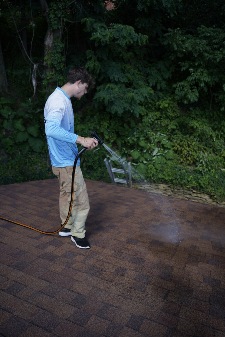 Roof cleaning service in South Point, PA applying a soft wash treatment to asphalt shingles to remove algae and dark staining.
